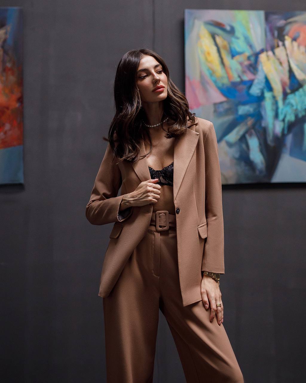 Woman in a brown suit standing in front of abstract paintings
