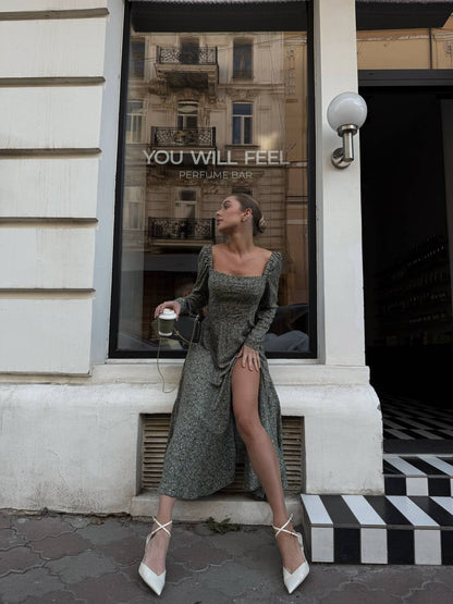 Woman in a long dress standing in front of a building with 'YOU WILL FEEL' perfume bar sign.