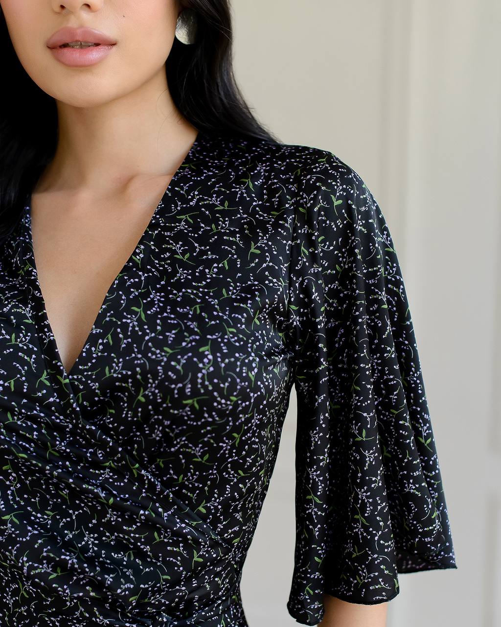 Woman wearing a black patterned dress against a neutral background