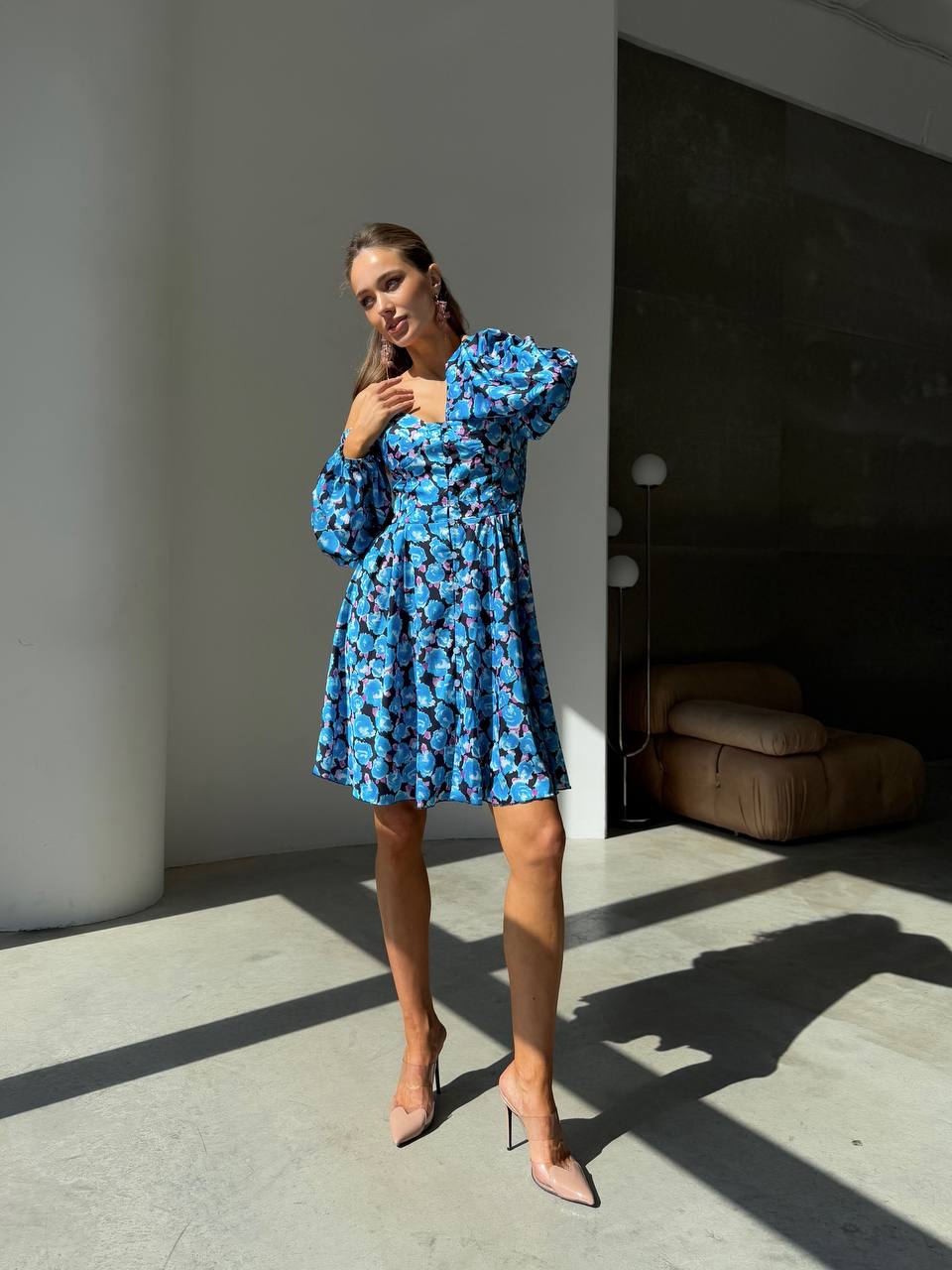 Woman wearing a blue floral dress standing in a modern indoor setting.