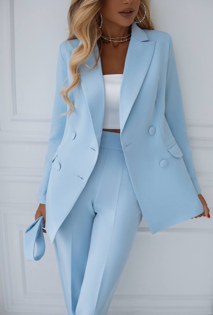 Woman wearing a light blue suit with a white top against a white background