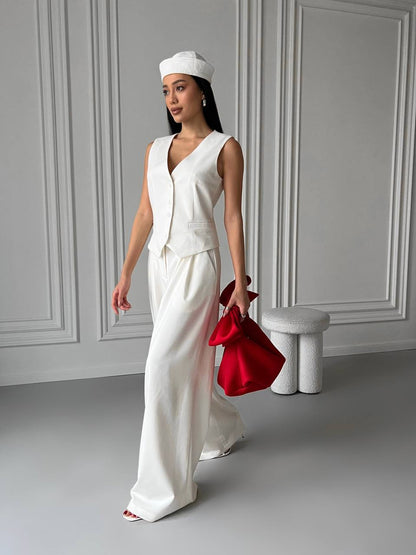 Woman in a white outfit holding a red bag in a minimalistic setting