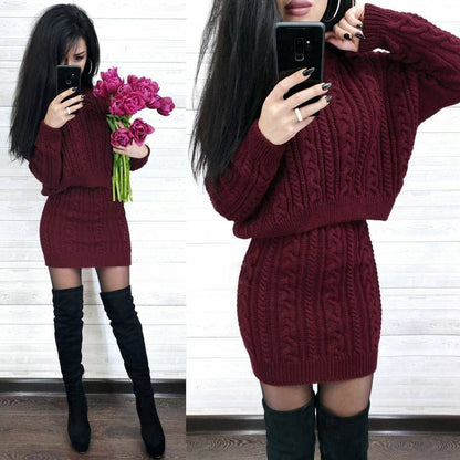 Woman wearing a burgundy cable knit sweater dress with black knee-high boots, holding pink flowers.