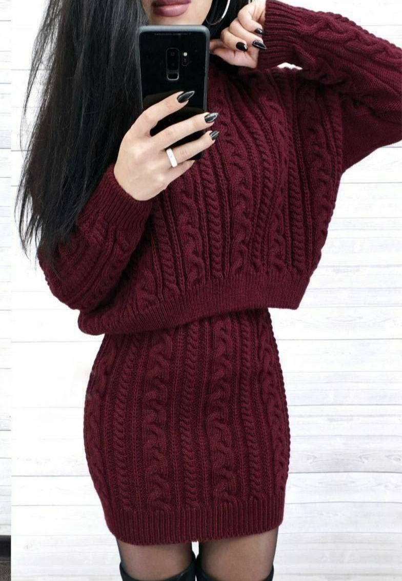 Person wearing a maroon cable knit sweater dress against a white background