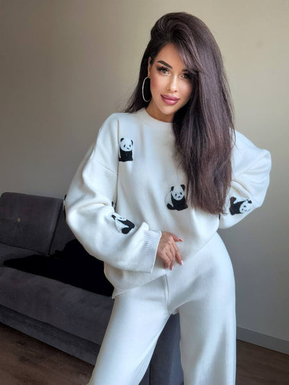 Woman wearing a white sweater with panda patterns in a room.