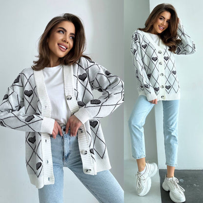 Woman wearing a white cardigan with black heart patterns, light blue jeans, and white sneakers.