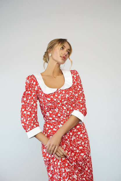 Woman wearing a red floral dress with white accents on a gray background