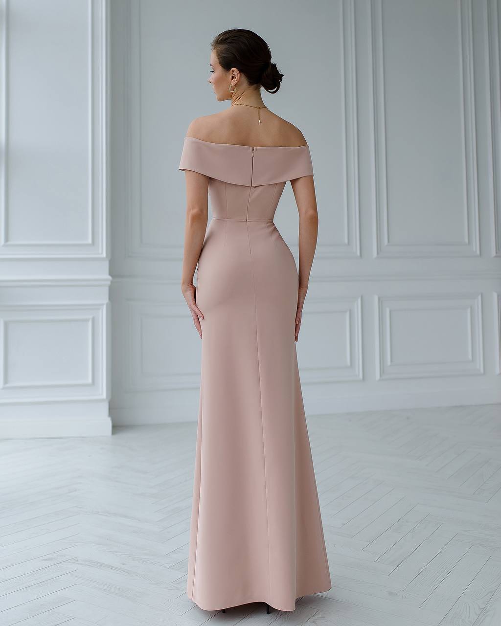 Woman wearing a pink off-shoulder gown in a white room