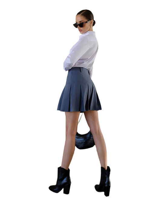 Woman wearing a white shirt, blue pleated skirt, and black boots on a white background