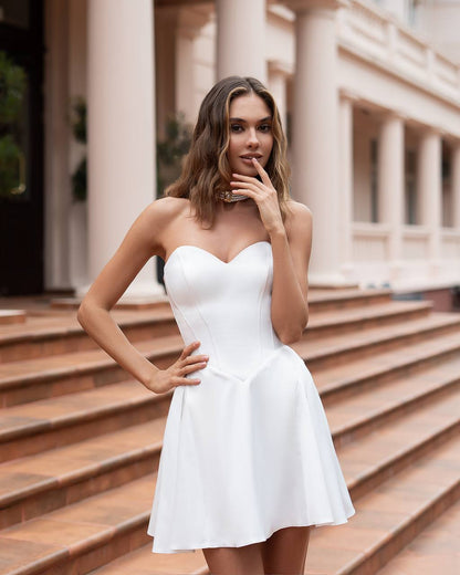 Woman in a white dress standing on steps with classical architecture in the background