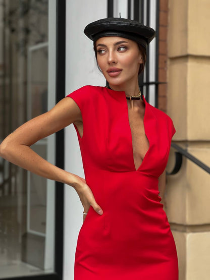 Woman wearing a red dress and black beret standing in an urban setting.