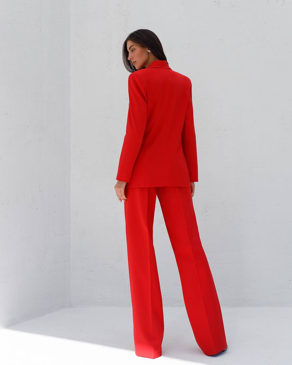 Person wearing a red suit standing against a white background