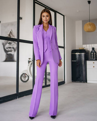 Woman wearing a purple suit standing in a modern interior setting.