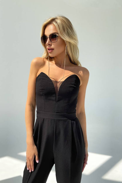 Woman wearing a black strapless jumpsuit against a light background