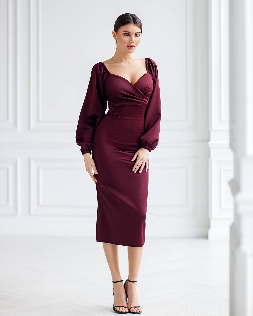 Woman wearing a burgundy dress with balloon sleeves against a white background