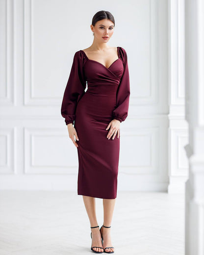 Woman wearing a burgundy dress with balloon sleeves against a white background