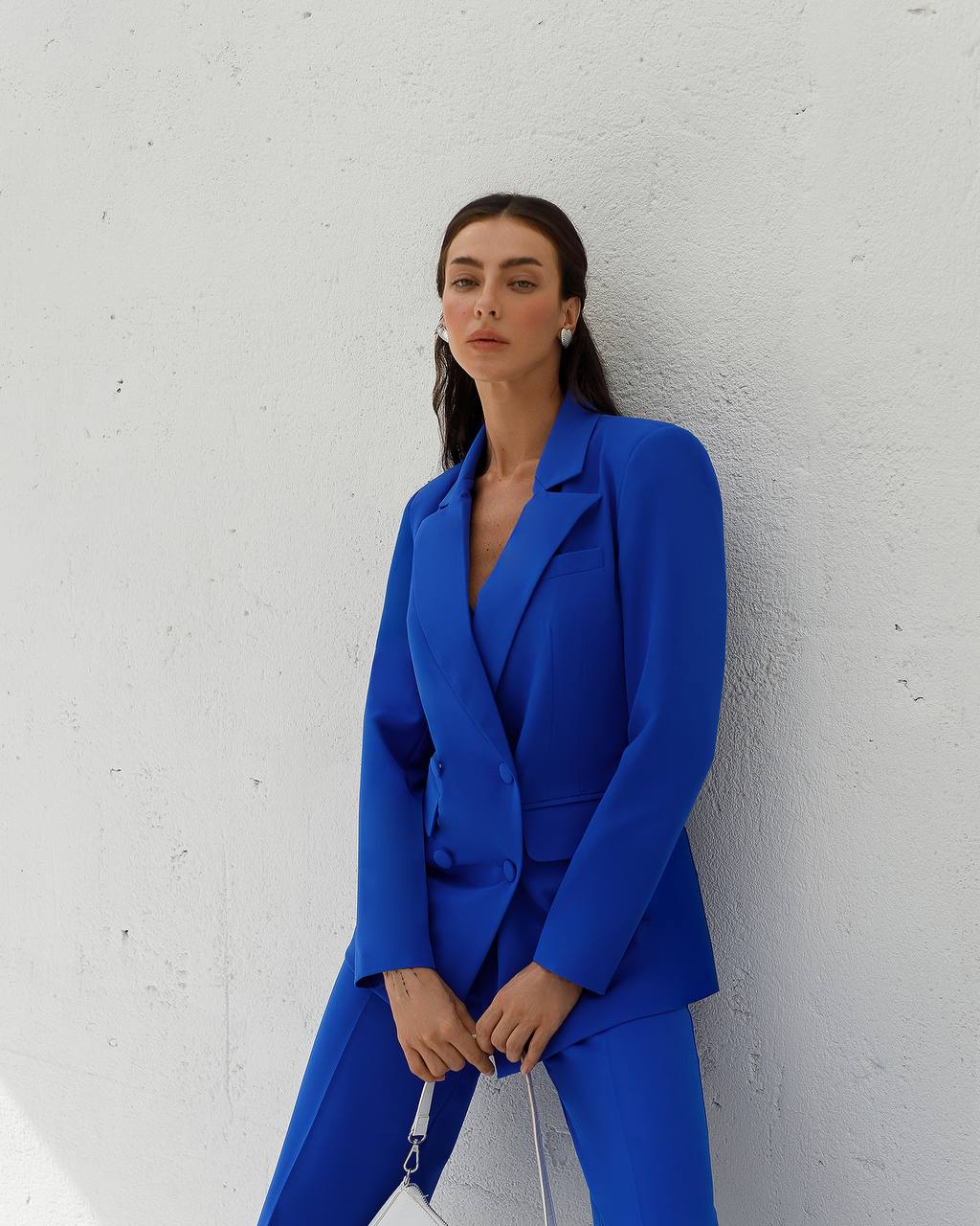 Woman wearing a blue suit against a white wall