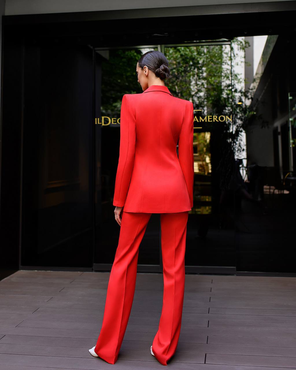 Person wearing a red suit standing in front of a store entrance.