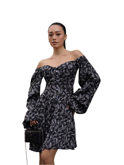 Woman wearing a black and white patterned off-shoulder dress on a white background