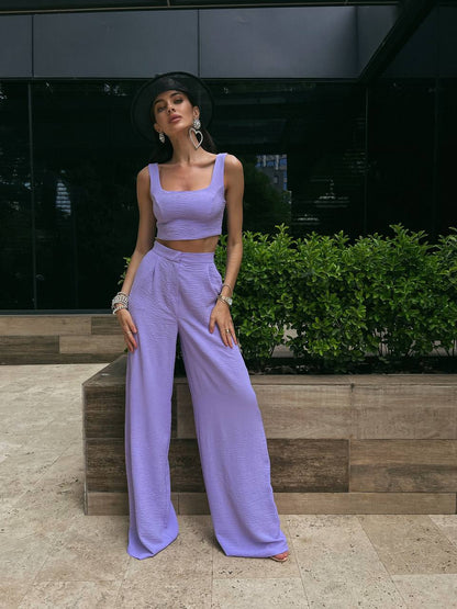Woman in a lavender outfit standing outdoors with a building in the background