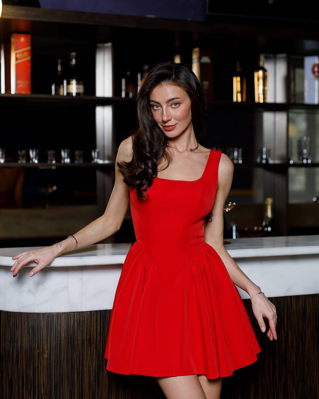 Woman in a red dress standing in a bar setting