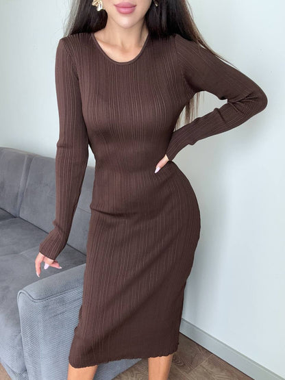 Woman wearing a brown ribbed dress standing in a room with a gray couch.