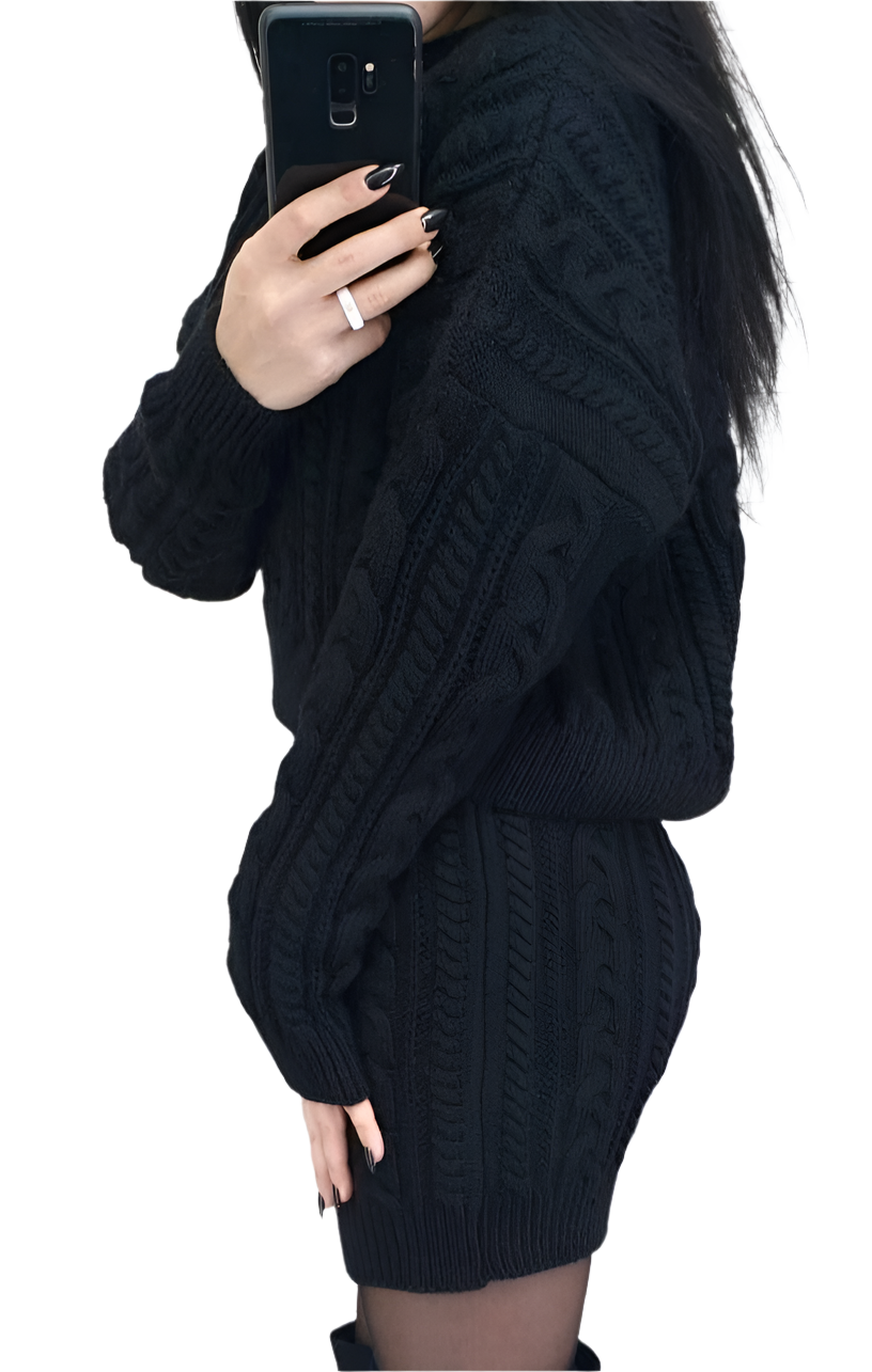 Person wearing a black cable knit sweater taking a mirror selfie.