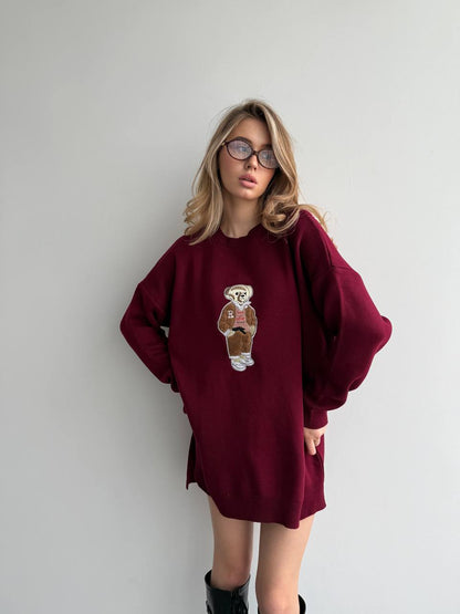 Person wearing a burgundy sweatshirt with a teddy bear graphic against a plain background