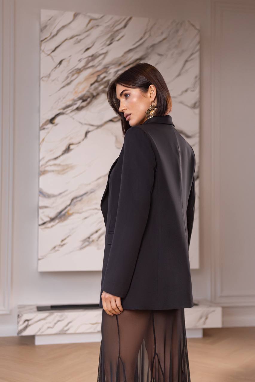 Woman in a black outfit standing in front of a marble wall.