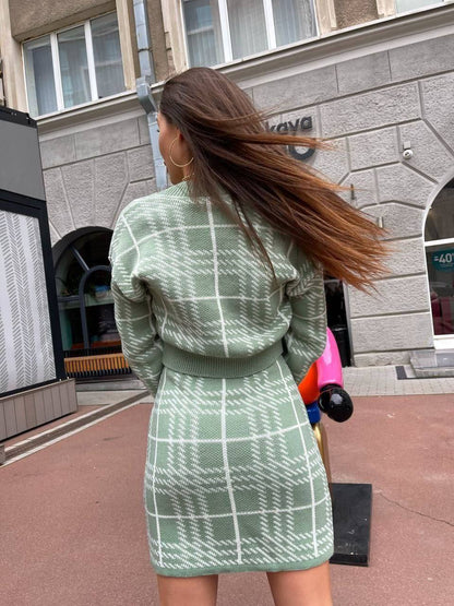 Woman in a green plaid outfit walking outdoors with a building in the background