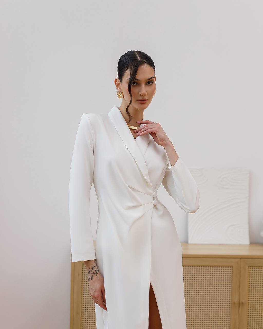 Woman wearing a white long coat against a plain background