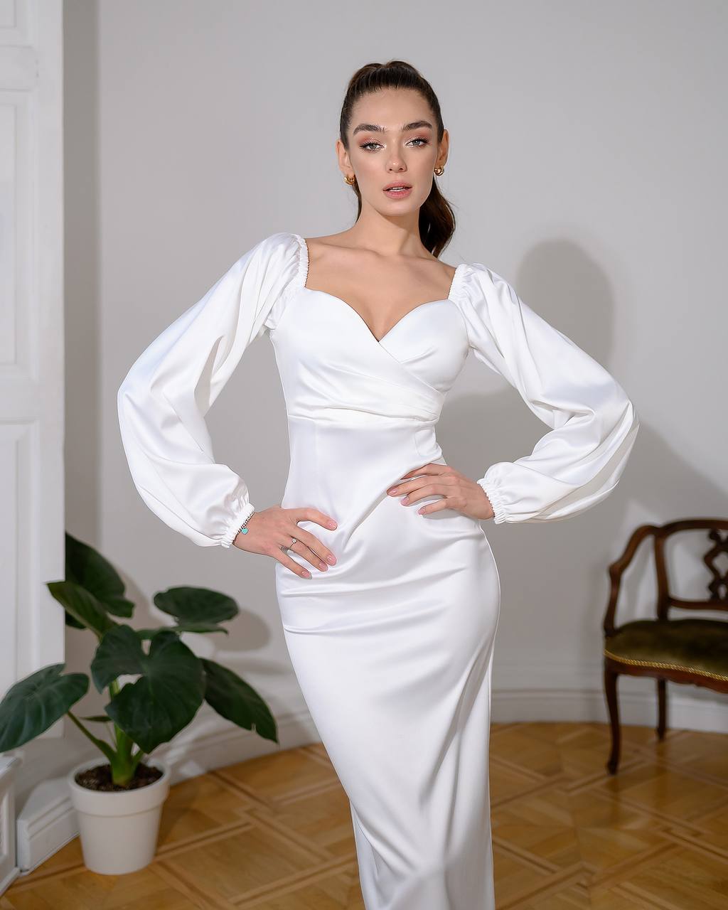 Woman wearing a white dress with long sleeves in an indoor setting.