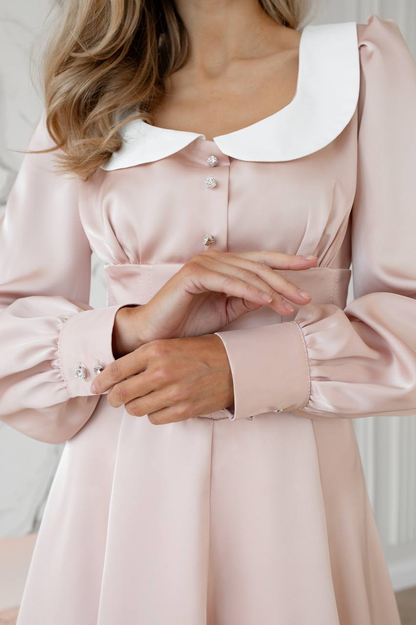 Pink dress with a white collar worn by a person, with a neutral background
