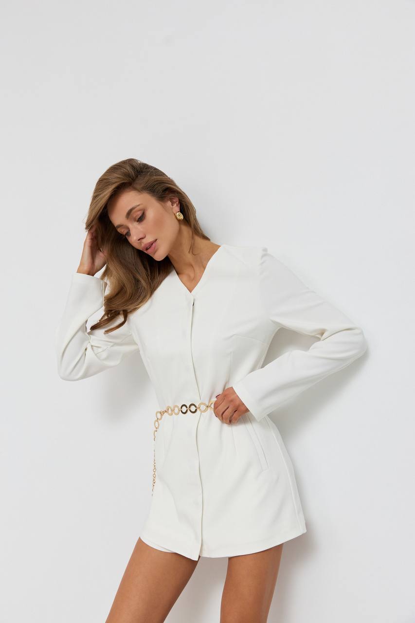 Woman wearing a white outfit with a belt on a plain background