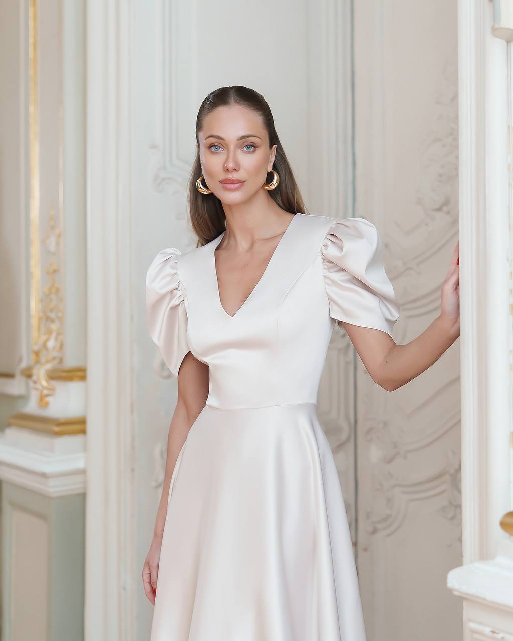 Woman wearing a white dress with puffed sleeves in an elegant interior setting