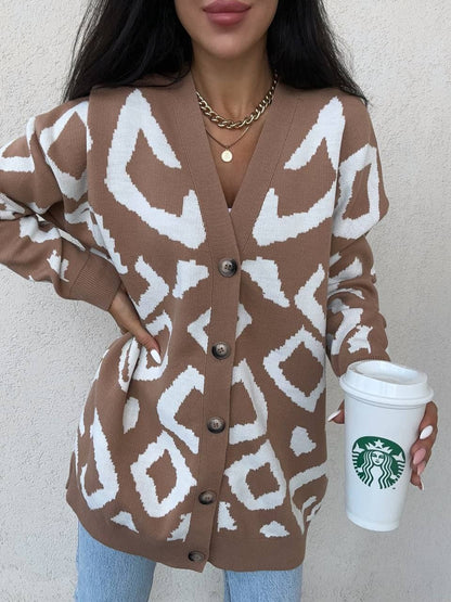 Person wearing a brown and white patterned cardigan holding a Starbucks cup.