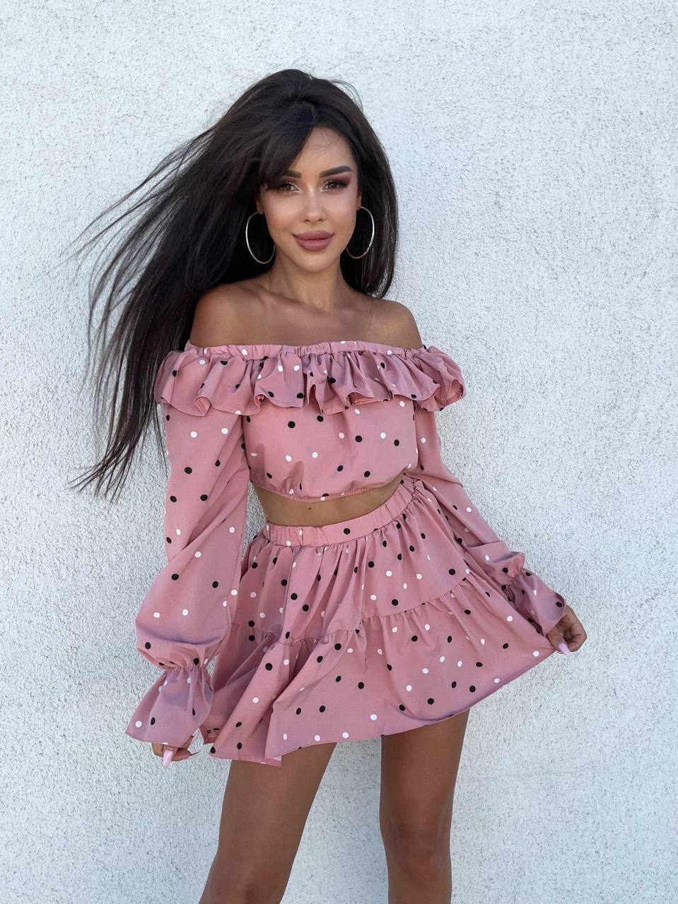 Woman wearing a pink polka dot outfit against a light background