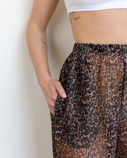 Person wearing leopard print pants with a plain background