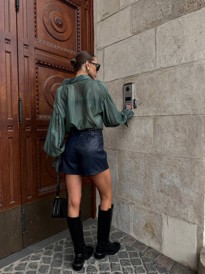 Person using a doorbell on a stone wall with a wooden door in the background