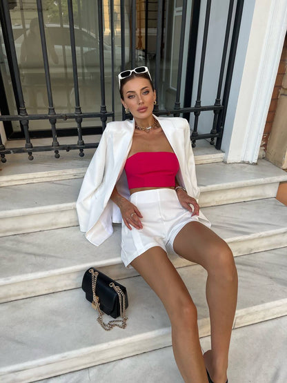 Woman in a white outfit with a red top sitting on steps.