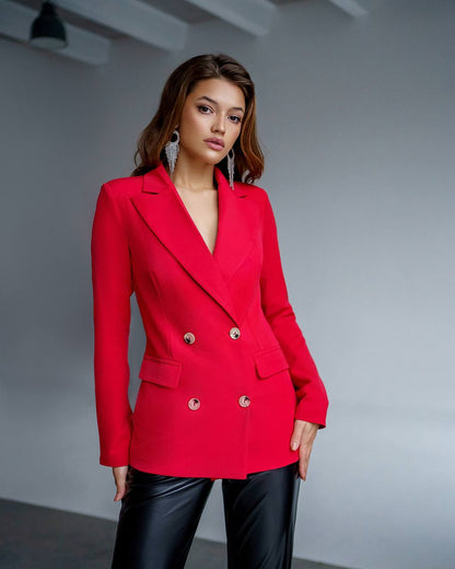Woman wearing a red blazer with gold buttons against a gray background