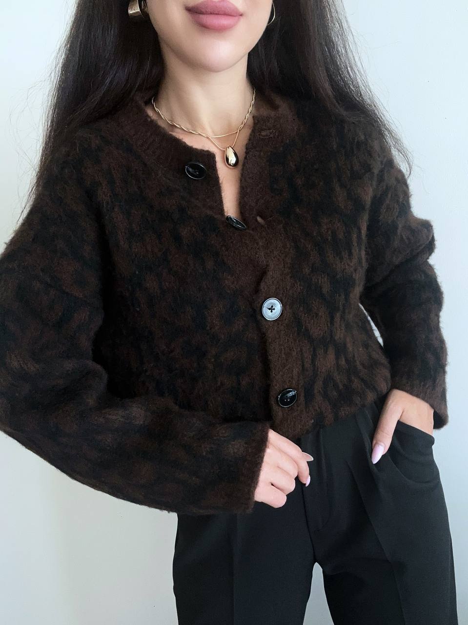 Person wearing a brown leopard print jacket with a plain background