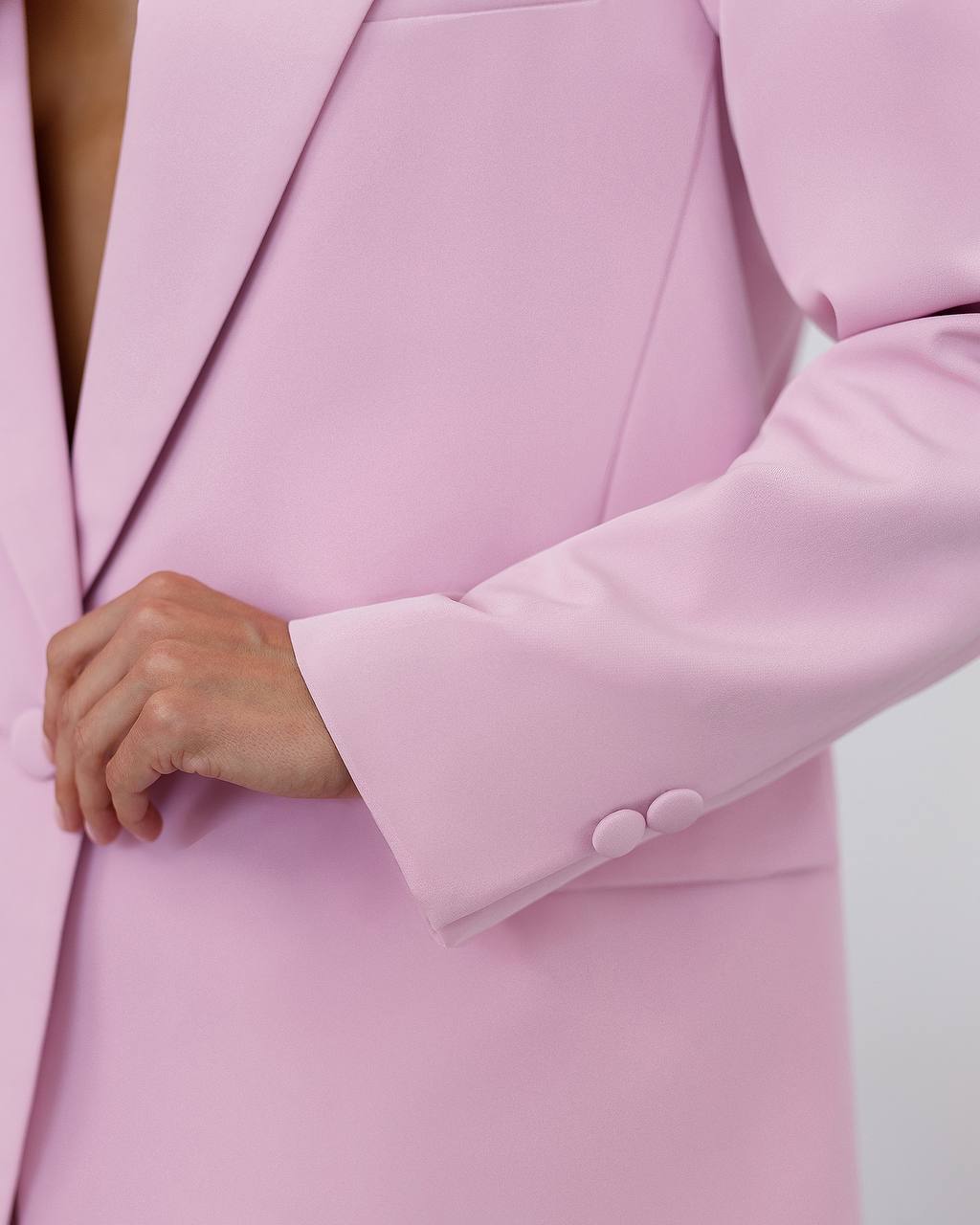 Close-up of a pink blazer with a button being pressed.