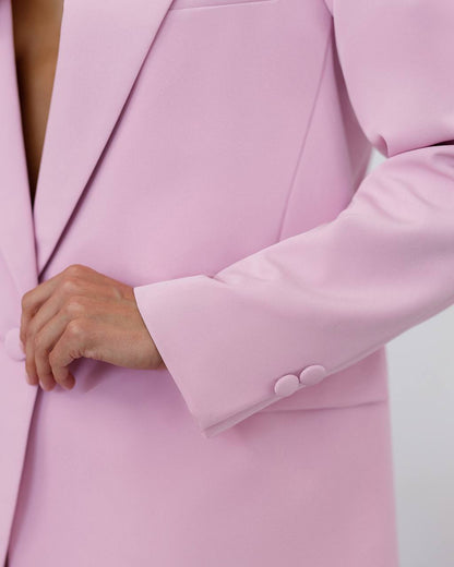 Close-up of a pink blazer with a button being pressed.