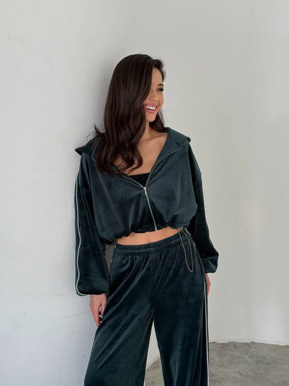 Woman wearing a dark green tracksuit against a plain background