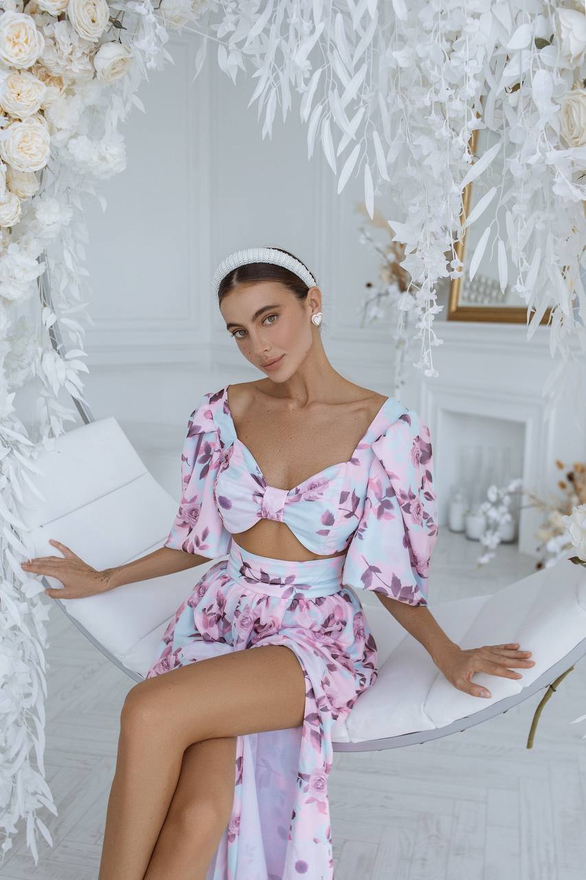 Woman in a floral dress sitting on a white chair with a decorated background