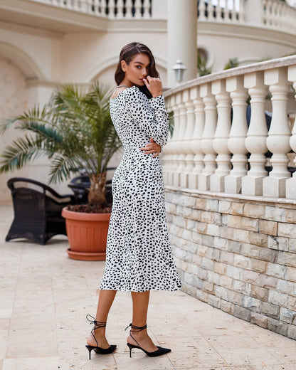 Woman in a polka dot dress standing on a balcony with decorative elements.