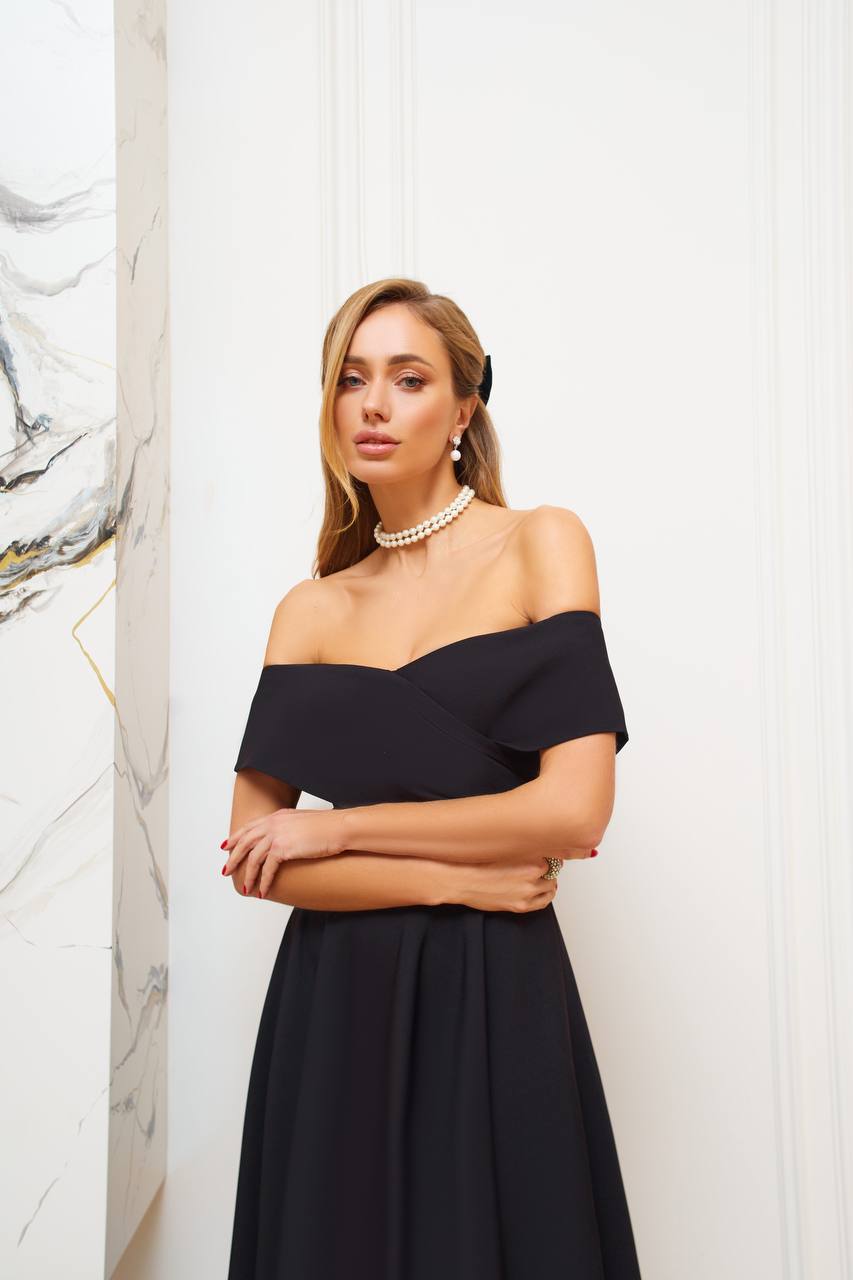 Woman wearing a black off-shoulder dress with a white background