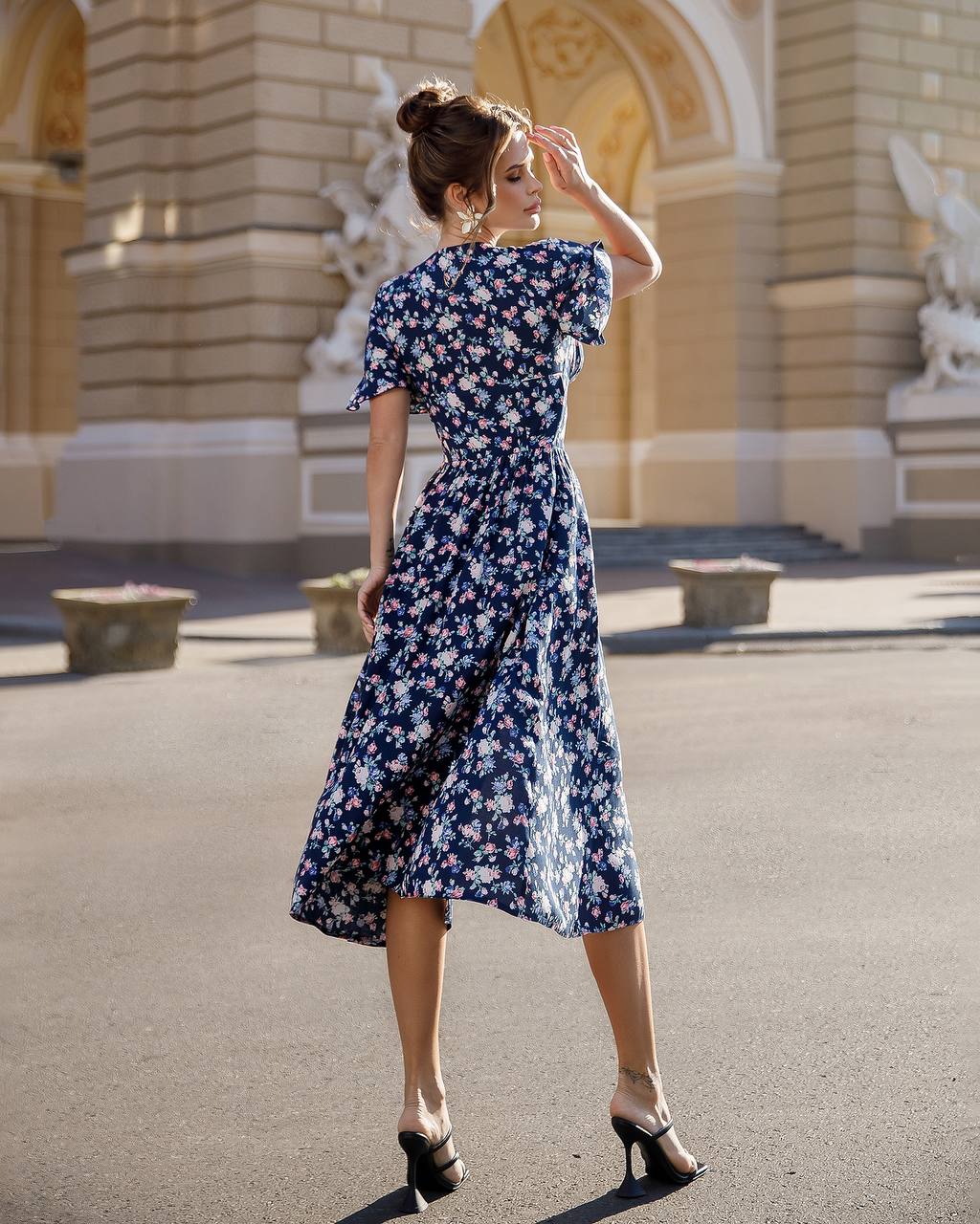 Woman in a floral dress standing in front of an architectural building
