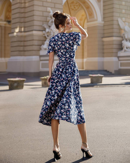Woman in a floral dress standing in front of an architectural building